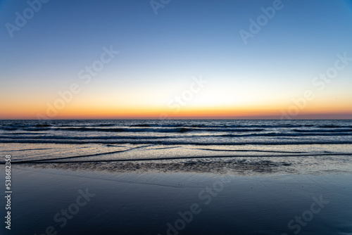 Sundown at the Dutch coastline between Noordwijk and Zandvoort. On the clear bright yellow and orange horizon. photo