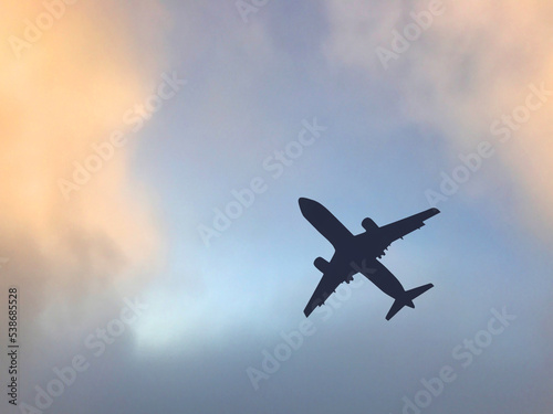 Silhouette of a passenger jet clambing after take off againsg a colourful clody sky. No people. Copy space.