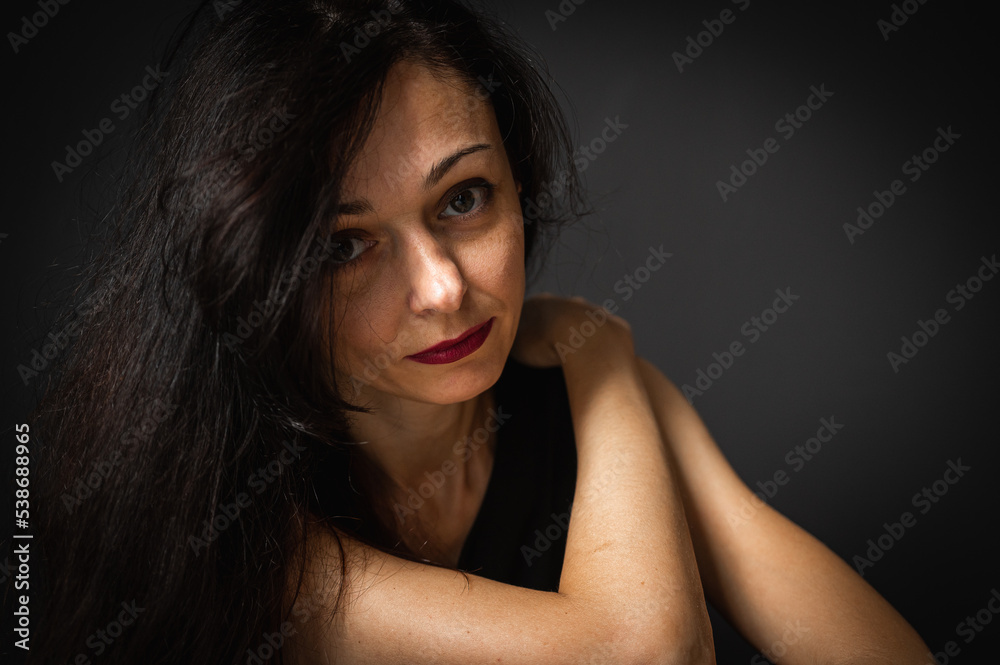 emotional portrait of a young beautiful girl sitting on the floor, pensive, thinking, depression, dark background, low key