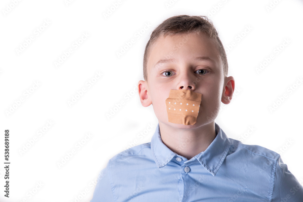 Portrait of a child in a blue shirt with a plaster on his mouth to keep him silent Portrait of a child in a blue shirt with a plaster on his mouth to keep him silent