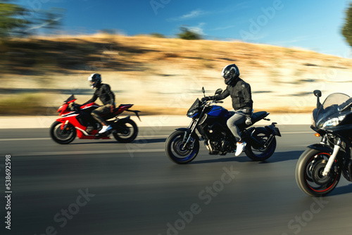 Three supersport race motorcycle riders going fast side by side on the highway with motion blur.