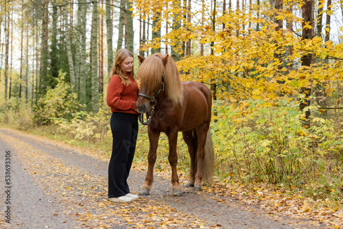Young female equestrian posing with Icelandic horse in in autumn scenery © AnttiJussi