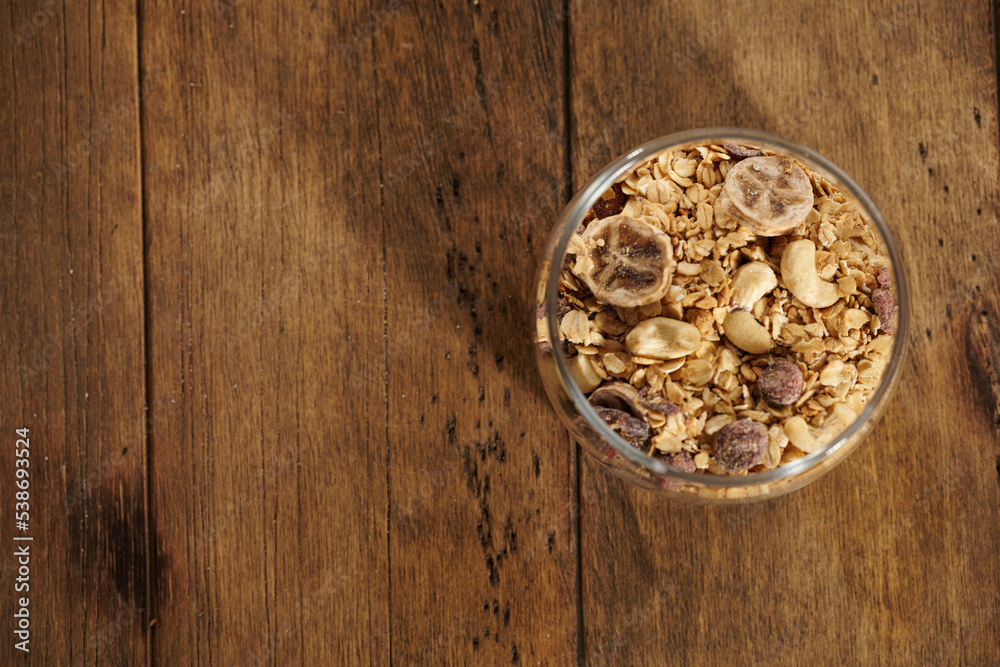 granola with dried fruits in a jar on a wooden table granola with dried fruits in a jar on a wooden table