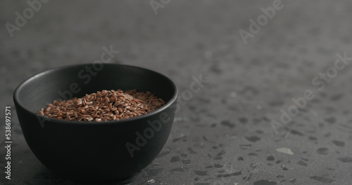 flaxseed in black bowl on terrazzo countertop with copy space