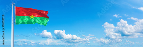 Burkina Faso flag waving on a blue sky in beautiful clouds - Horizontal banner photo