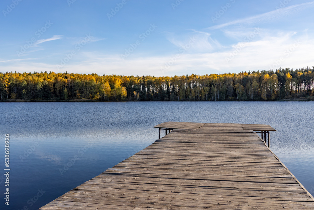 Obraz premium Wooden deck near the water. Sunny autumn day near the pond.