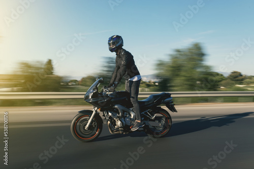 Fototapeta Naklejka Na Ścianę i Meble -  Side view of a motorcycle rider riding race motorcycle on foot on the highway with motion blur.