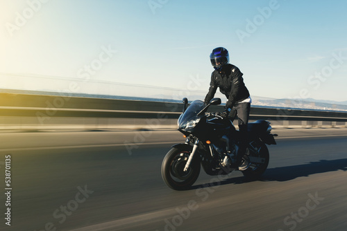 Side view of a motorcycle rider riding race motorcycle on foot on the highway with motion blur.