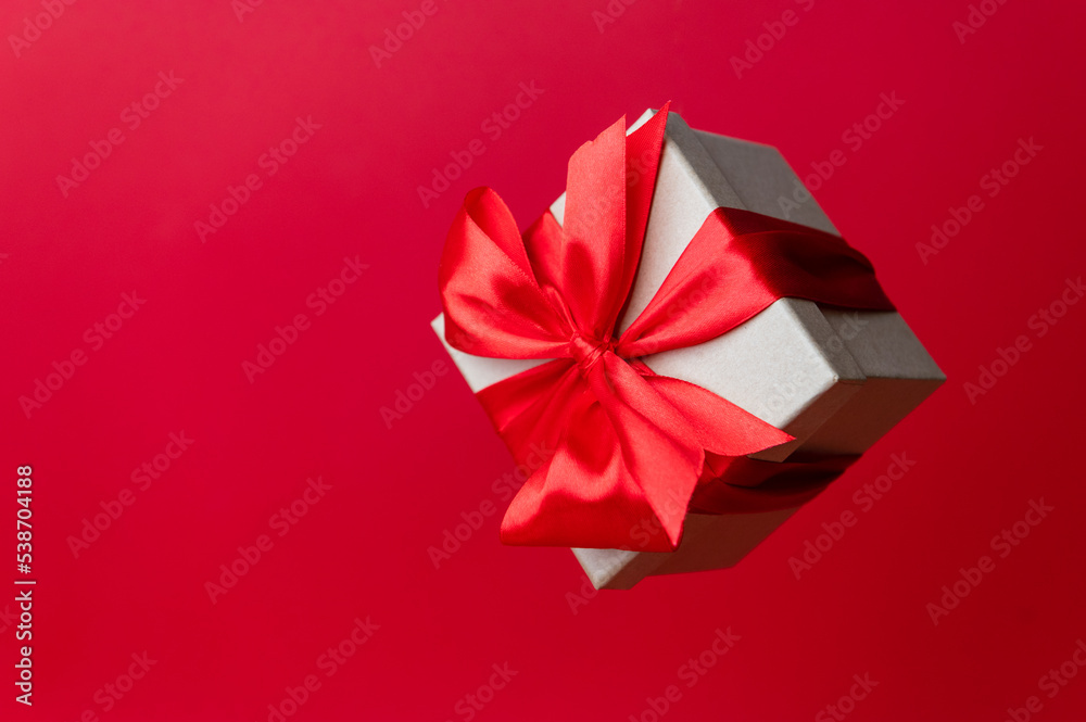 Gorgeous festive Christmas banner or header, holiday present on red background. Christmas floating gift box on red. Holiday season, New Year. Copy space for text. Gorgeous festive Christmas banner or header, holiday present on red background. Christmas floating gift box on red. Holiday season, New Year. Copy space for text.