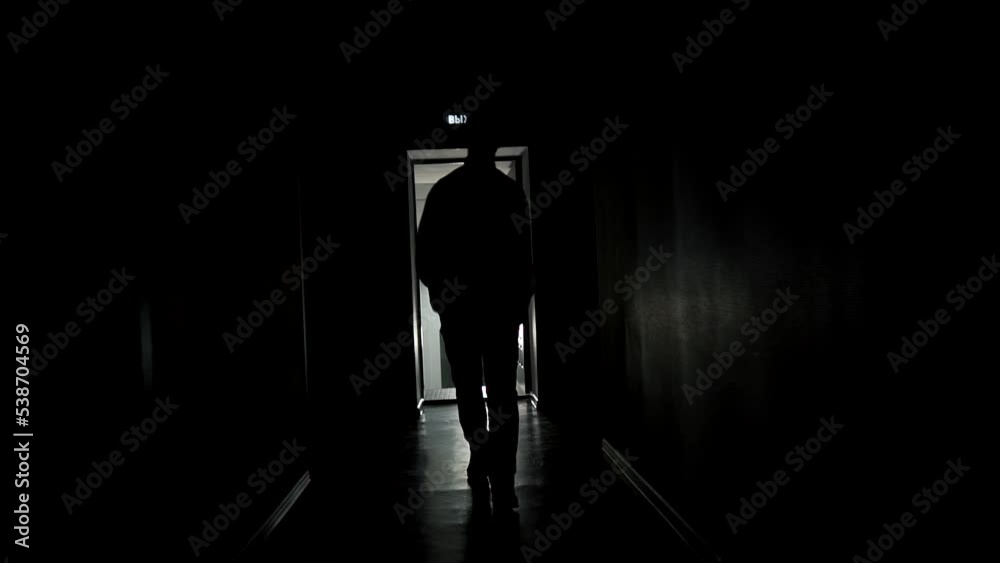 Slow motion, a dark man walks along the corridor of an office or hotel. backlight, a mysterious silhouette goes to the camera. High quality FullHD footage