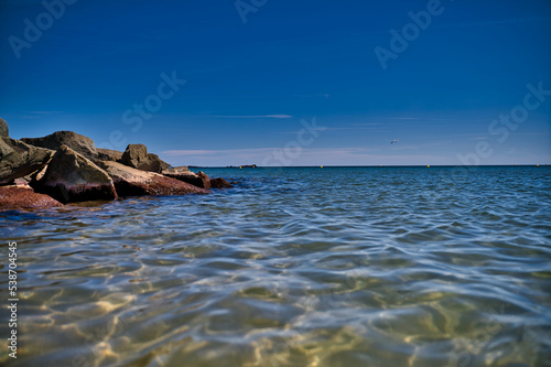Ausblick auf das Meer mit blauem Himmel und Wellenbrecher