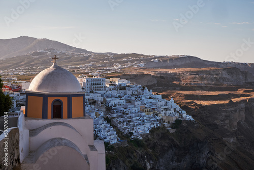 Panoramic Aerial View of Fira Village and Catholic Church of Saint Stylianos in Santorini Island, Greece - Traditional White Houses in the Caldera Cliffs photo