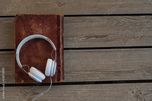headphones on old book and wooden background