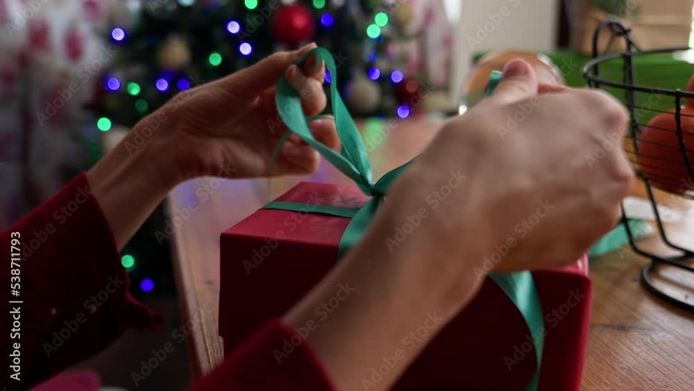 Woman wrapping and tying ribbon on Christmas gift box. Woman wrapping and tying ribbon on Christmas gift box.