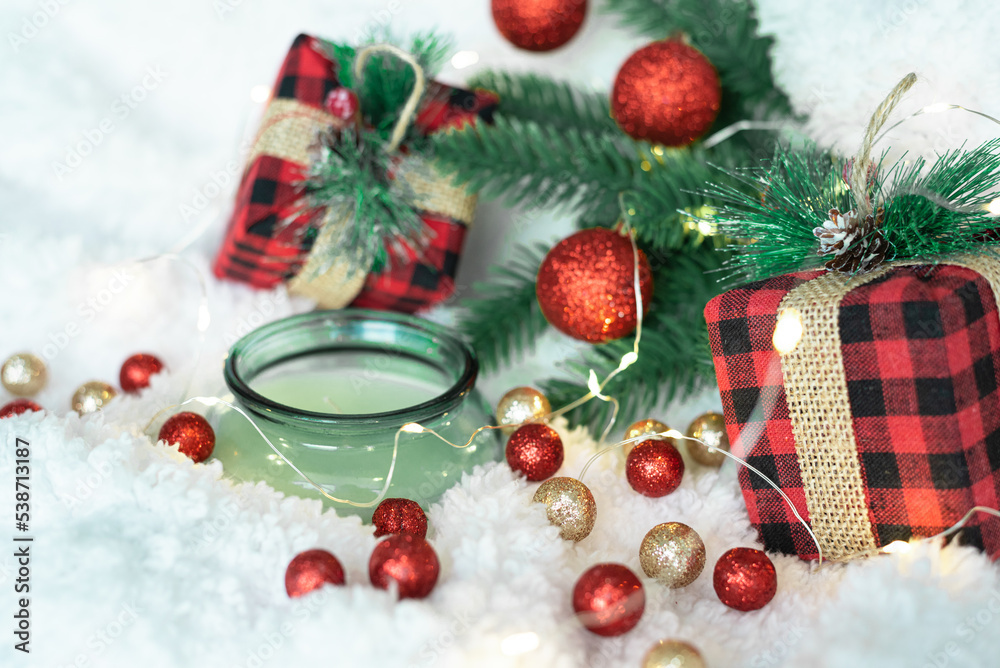 Decor of green shiny Christmas balls, lights of a Christmas garland on a white fluffy soft background. Cozy holidays. New Year holidays 2023. Place for text. Postcard for the New Year and Christmas.