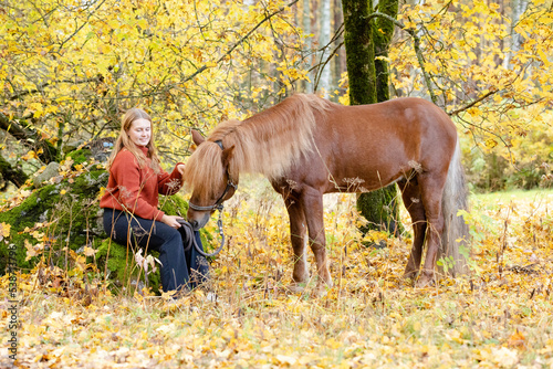Young woman under yellow maple tree with Icelandic horse © AnttiJussi