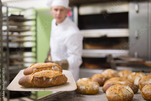 Baker takes out hot bread from the oven