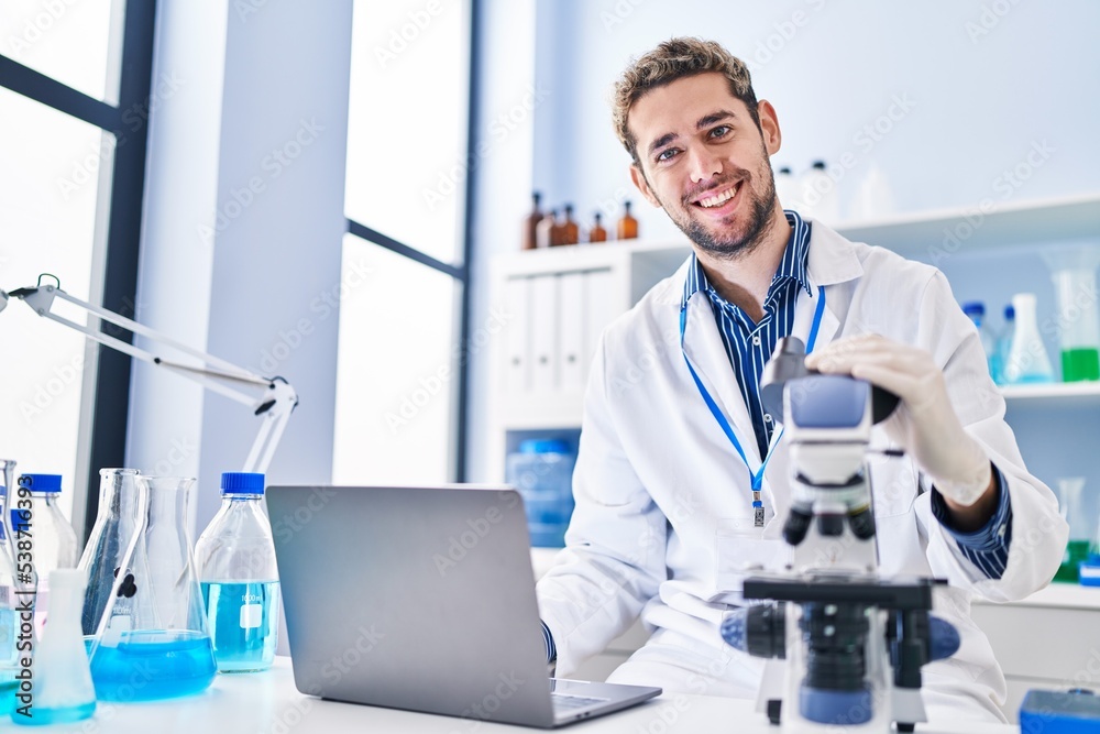 Young man scientist using laptop and microscope at laboratory Young man scientist using laptop and microscope at laboratory