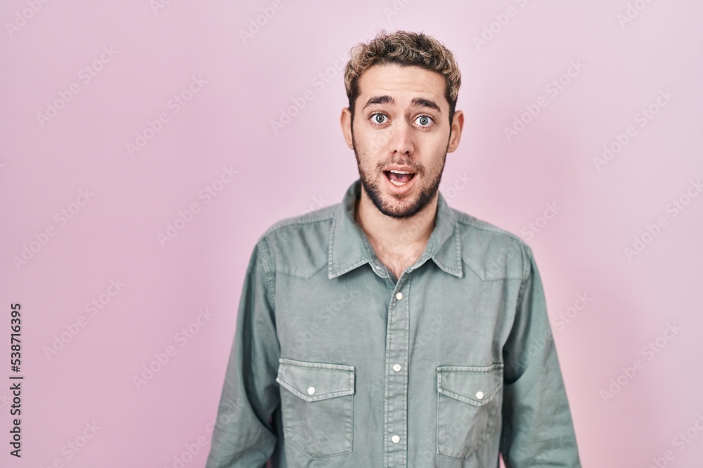 Obraz premium Hispanic man with beard standing over pink background afraid and shocked with surprise expression, fear and excited face.