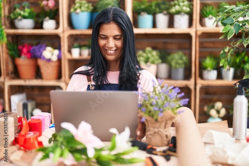 Middle age hispanic woman florist smiling confident using laptop at florist