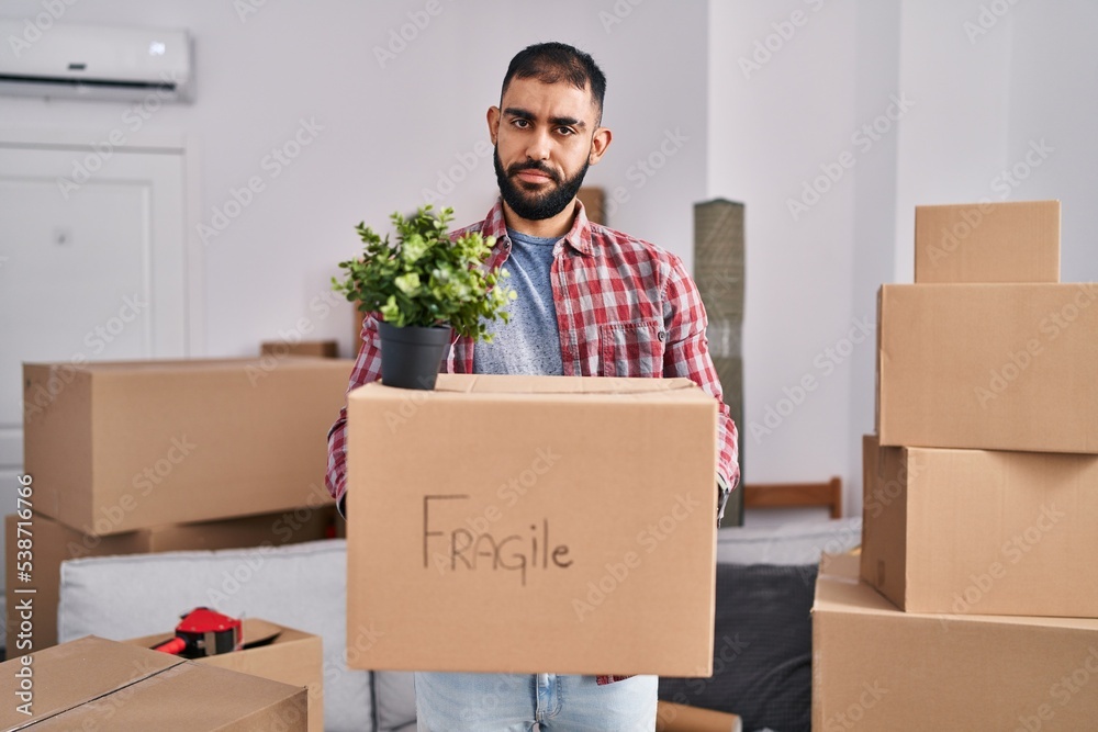 Middle east man with beard moving to a new home holding cardboard box skeptic and nervous, frowning upset because of problem. negative person. Middle east man with beard moving to a new home holding cardboard box skeptic and nervous, frowning upset because of problem. negative person.