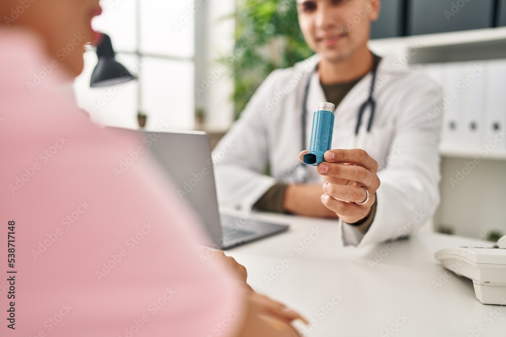 Obraz premium Man and woman doctor and patient having medical consultation holding inhaler at clinic