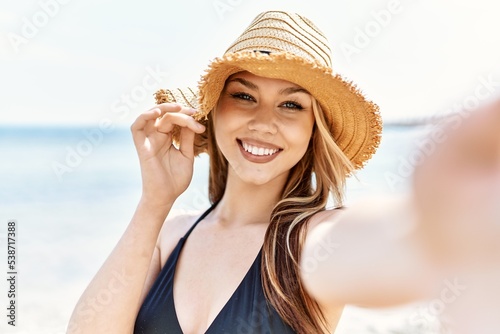 Young cuacasian girl smiling happy making selfie by the camera at the beach.