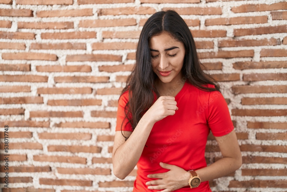 Young teenager girl standing over bricks wall feeling unwell and coughing as symptom for cold or bronchitis. health care concept. Young teenager girl standing over bricks wall feeling unwell and coughing as symptom for cold or bronchitis. health care concept.