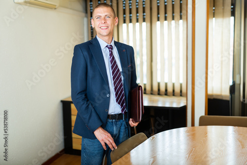 Positive experienced american businessman with briefcase standing in the office