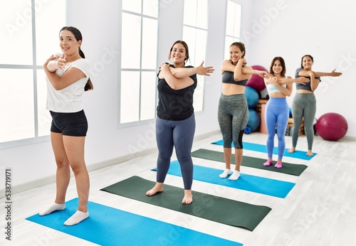 Group of young hispanic women smiling happy training yoga at sport center.