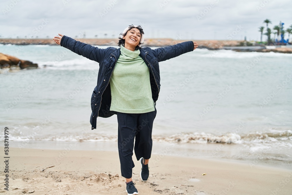 Young beautiful hispanic woman smiling confident standing with arms open at seaside Young beautiful hispanic woman smiling confident standing with arms open at seaside