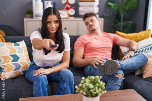 Man and woman couple watching television sitting on sofa at home