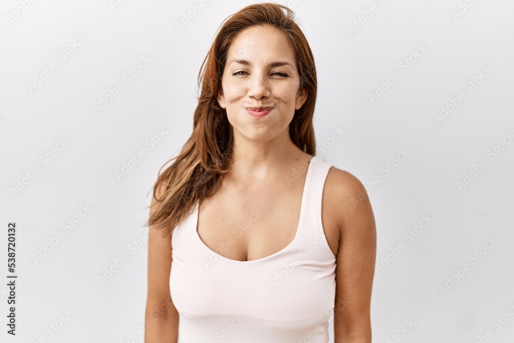 Middle age hispanic woman standing over isolated background puffing cheeks with funny face. mouth inflated with air, crazy expression. Middle age hispanic woman standing over isolated background puffing cheeks with funny face. mouth inflated with air, crazy expression.