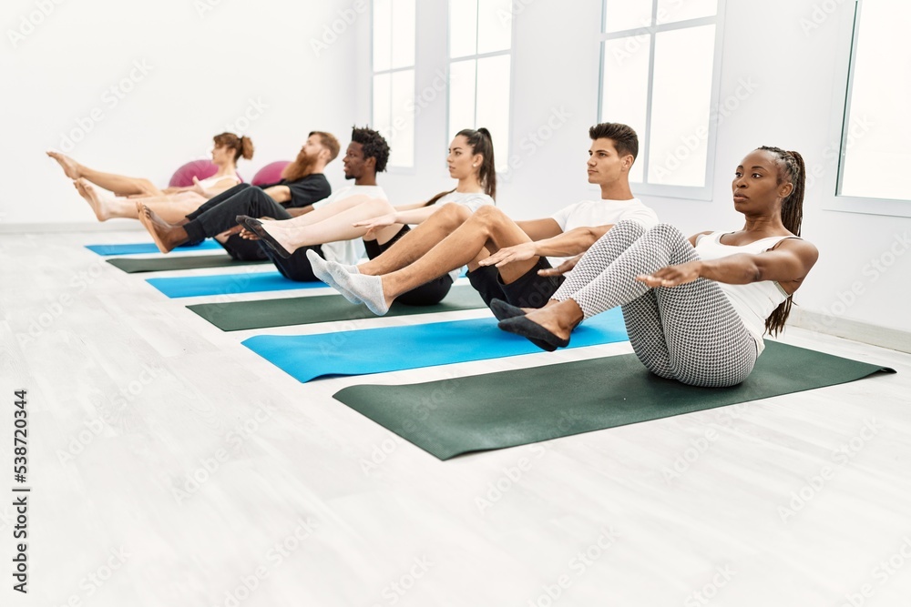 Group of young people concentrate training yoga at sport center.