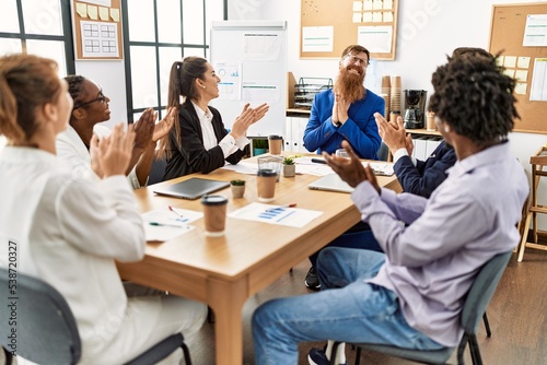 Group of business workers smiling and clapping to partner at the office.