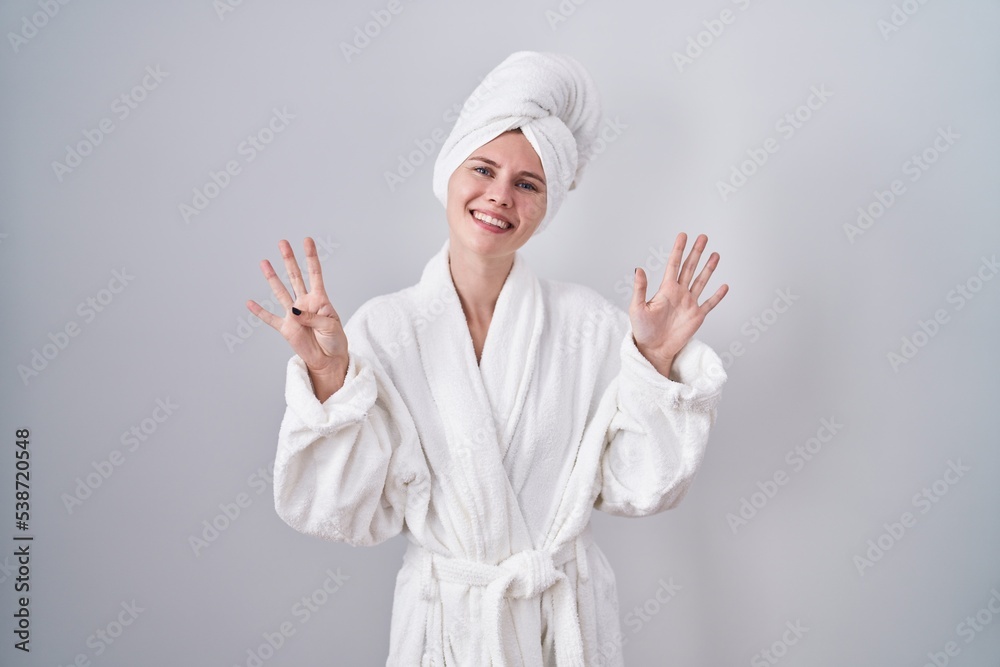 Blonde caucasian woman wearing bathrobe showing and pointing up with fingers number nine while smiling confident and happy. Blonde caucasian woman wearing bathrobe showing and pointing up with fingers number nine while smiling confident and happy.