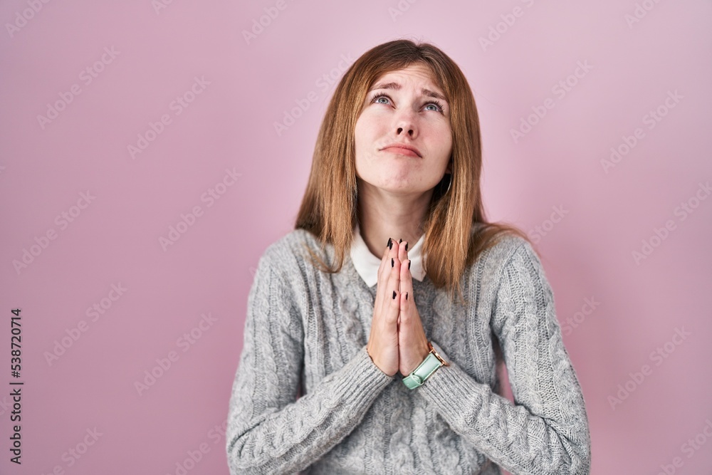 Beautiful woman standing over pink background begging and praying with hands together with hope expression on face very emotional and worried. begging. Beautiful woman standing over pink background begging and praying with hands together with hope expression on face very emotional and worried. begging.