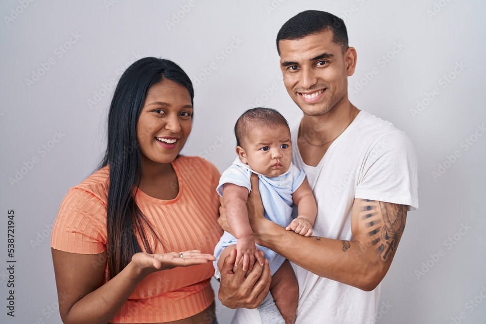 Young hispanic couple with baby standing together over isolated background pointing aside with hands open palms showing copy space, presenting advertisement smiling excited happy Young hispanic couple with baby standing together over isolated background pointing aside with hands open palms showing copy space, presenting advertisement smiling excited happy