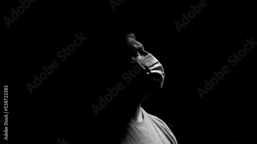 Male wearing surgical mask on a dark background.