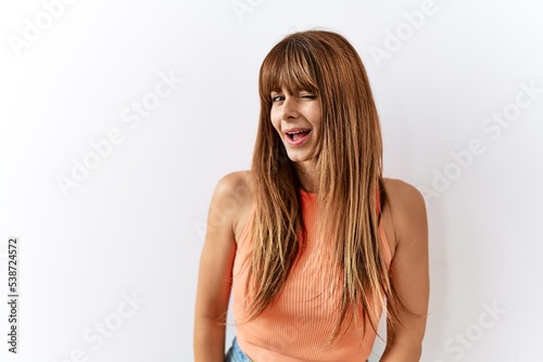 Hispanic woman with bang hairstyle standing over isolated background winking looking at the camera with sexy expression, cheerful and happy face.