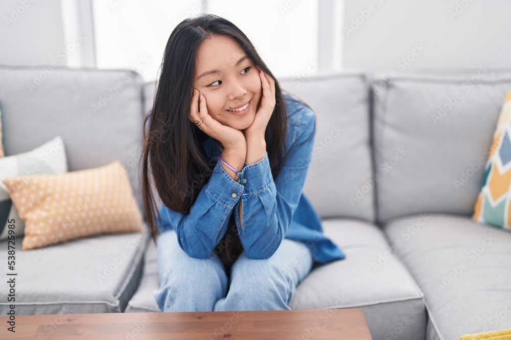 Young chinese woman smiling confident sitting on sofa at home Young chinese woman smiling confident sitting on sofa at home