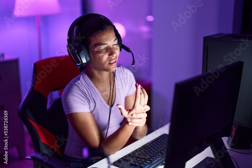 Young beautiful hispanic woman streamer stressed using computer at gaming room