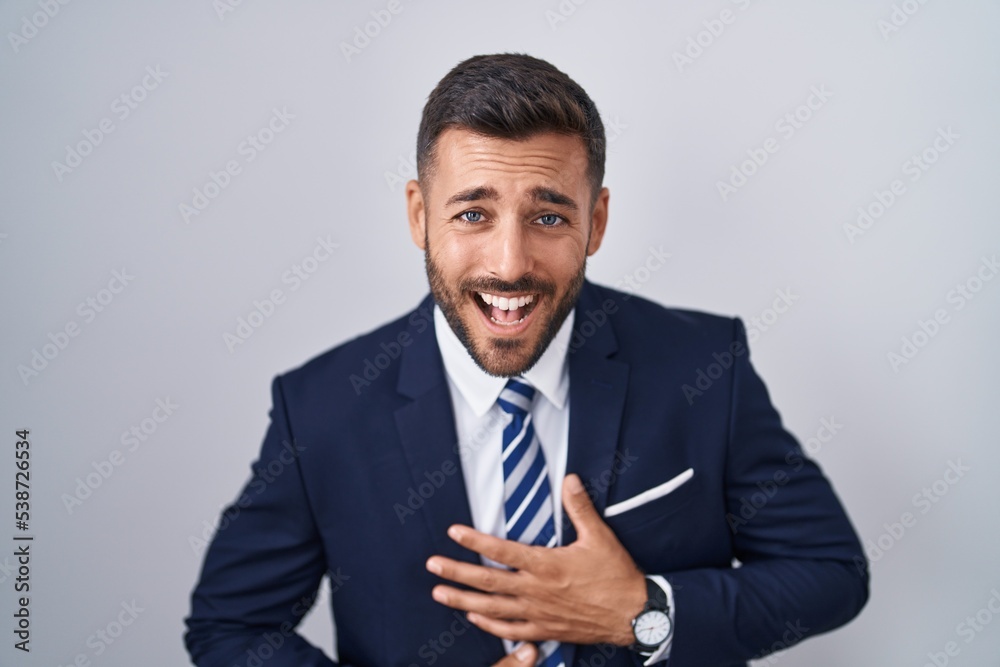 Handsome hispanic man wearing suit and tie smiling and laughing hard out loud because funny crazy joke with hands on body. Handsome hispanic man wearing suit and tie smiling and laughing hard out loud because funny crazy joke with hands on body.