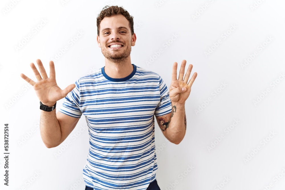 Fototapeta premium Handsome young man standing over isolated background showing and pointing up with fingers number nine while smiling confident and happy.