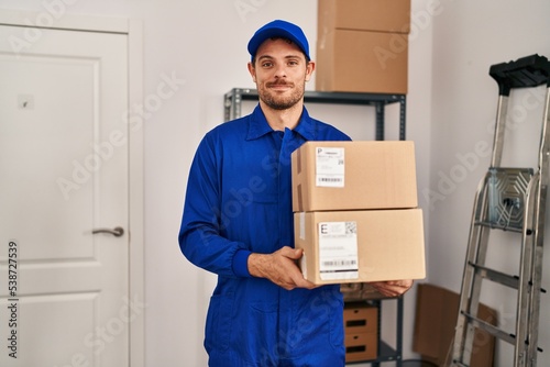 Young hispanic man working on moving service holding boxes relaxed with serious expression on face. simple and natural looking at the camera. © Krakenimages.com