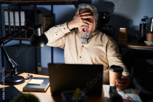 Wallpaper Mural Middle age man with grey hair working at the office at night peeking in shock covering face and eyes with hand, looking through fingers with embarrassed expression. Torontodigital.ca