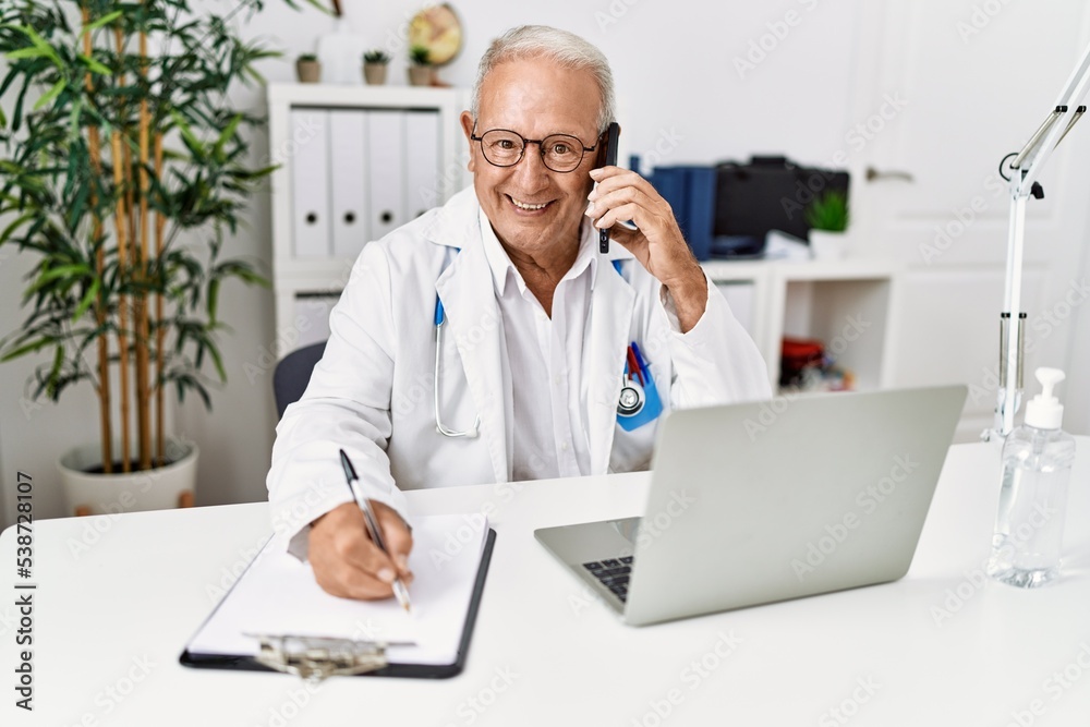 Senior man wearing doctor uniform talking on the smartphone at clinic