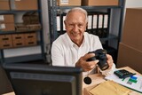 Senior man ecommerce business worker holding professional camera at office