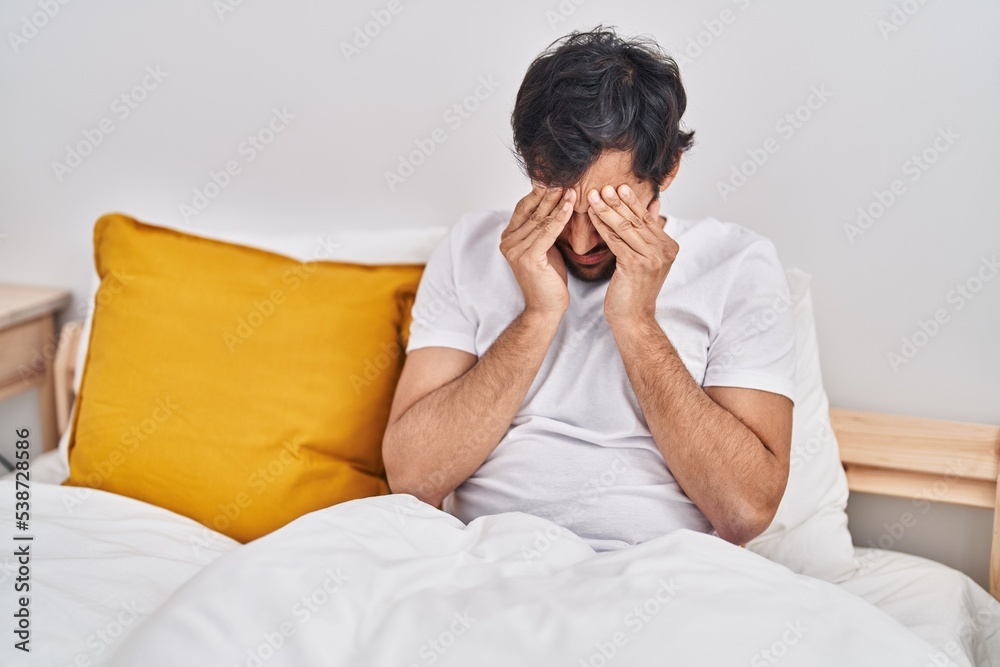 Young hispanic man sitting on bed crying at bedroom Young hispanic man sitting on bed crying at bedroom