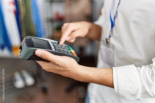 Young arab man smiling confident using data phone device at clothing store photo